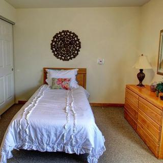 A simple bedroom with a single bed, wooden furniture, and decorative elements.