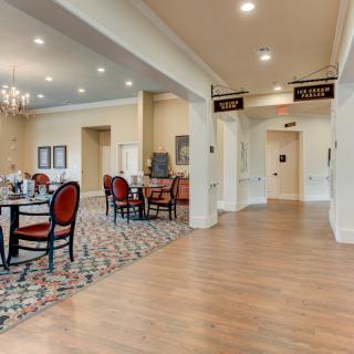 An elegant dining area with red cushioned chairs, tables, and ceiling lights.
