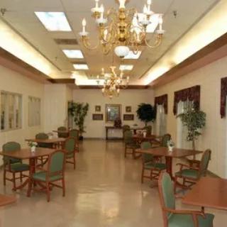 An elegant dining room with chandeliers, tables, and chairs, decorated with plants.