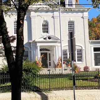 A historic white house with elegant architecture and a well-maintained garden.