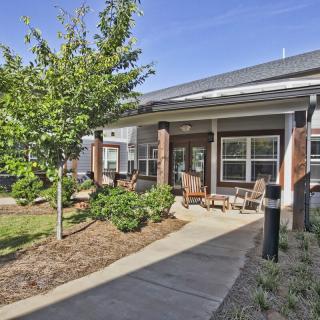 Outdoor seating area in front of a modern building with landscaped surroundings.