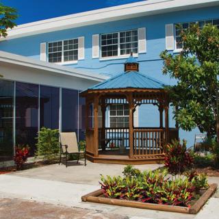 A blue house with a wooden gazebo and a small garden patch in the patio area.