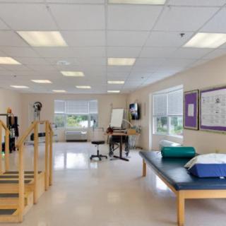 A spacious, well-lit rehabilitation center featuring various exercise equipment and therapy areas.