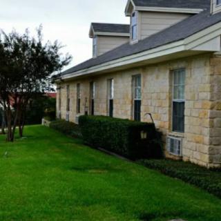 A residential house with a well-maintained lawn and stone exterior.