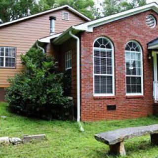 A brick house with arched windows and a wooden bench in the yard.
