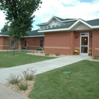 A brick residential building with a well-maintained lawn and pathway.