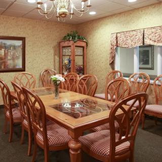 A well-appointed dining room with a large table and elegant chairs, adorned by a chandelier.
