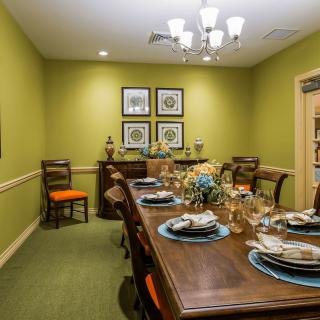 A neatly set dining room with green walls and traditional decor.