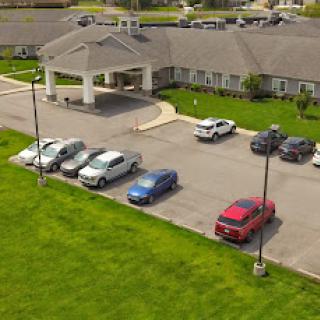 Aerial view of a hotel with a spacious parking lot and well-maintained lawn.