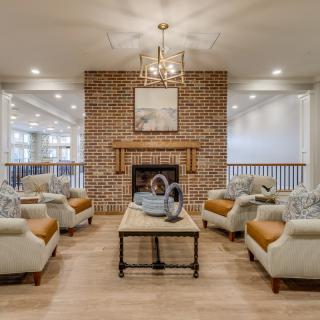 A cozy living room with a brick fireplace, surrounded by comfortable seating and a stylish chandelier.