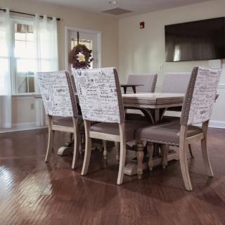 A cozy dining area with a wooden table and upholstered chairs set on a polished hardwood floor.
