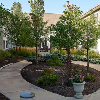 A beautifully landscaped courtyard with a winding pathway, surrounded by trees and shrubs.