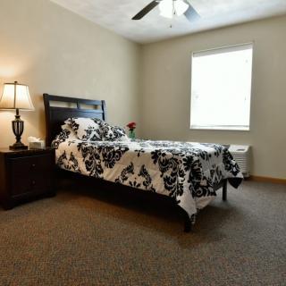 A neatly arranged bedroom with a single bed, nightstand, and lamp.