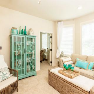 A bright living room with coastal decor featuring turquoise accents and a glass cabinet.
