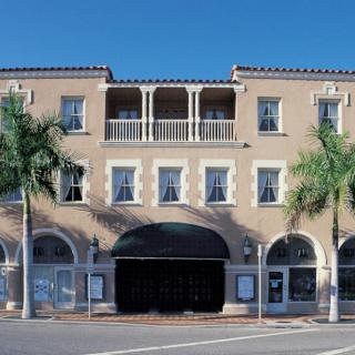 A Mediterranean-style building with palm trees and arched windows.