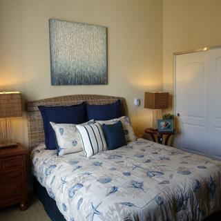 A cozy bedroom with a neatly made bed, flanked by two nightstands and lamps, featuring decorative artwork on the wall.