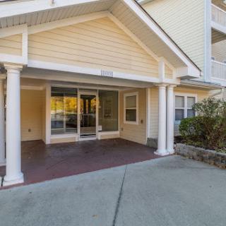 A welcoming entrance to a residential building featuring a spacious porch and glass doors.