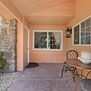 A cozy porch area with a table and two chairs, featuring a stone wall and windows.