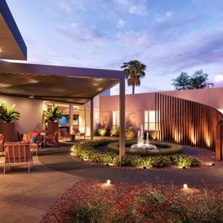 A modern outdoor space featuring a fountain and seating area under evening skies.