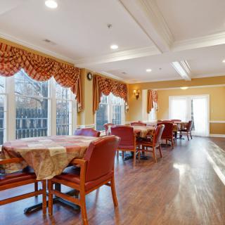 A well-lit dining room with elegant curtains and wooden floors.