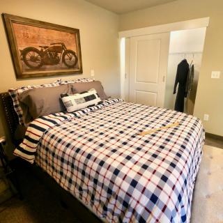 A cozy bedroom featuring a bed with plaid bedding and a motorbike picture on the wall.