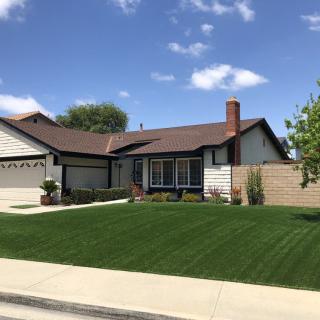 A suburban house with a well-maintained lawn and clear blue sky.