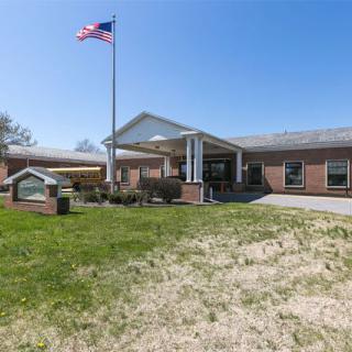 A single-story brick building with an American flag flying outside and a well-maintained entrance.