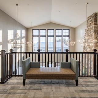 A modern living room with a couch and large windows, featuring chandeliers and abundant natural light.