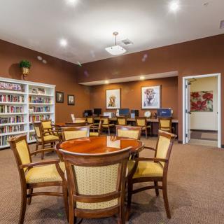 A cozy library reading area with chairs around a table and bookshelves filled with books.