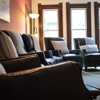 A cozy living room with comfortable chairs lined up by large windows.