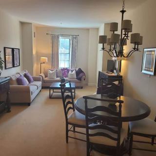 A cozy living room featuring a sofa, dining table, and elegant chandelier.