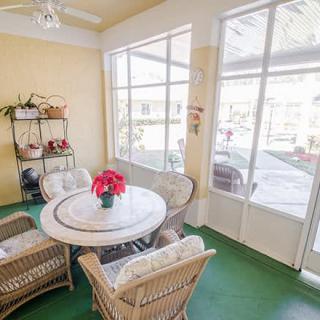 A bright sunroom featuring a round table with wicker chairs and large windows letting in natural light.