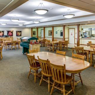 A spacious dining area with wooden tables and chairs, well-lit and neatly arranged.