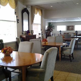 A spacious dining area with tables and upholstered chairs, featuring elegant decor and large windows.