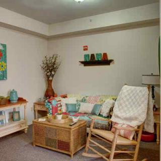 A cozy living room with colorful decorations and comfortable furniture, including a rocking chair and a sofa.