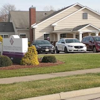 A view of a residential building with parked cars and well-maintained landscaping.