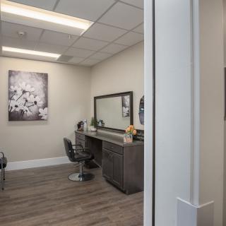 An empty modern hair salon with a styling chair and large mirror.