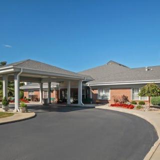 A building entrance with a driveway and landscaped surroundings under a clear sky.