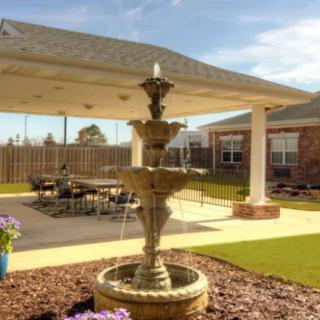 A serene outdoor patio featuring a multi-tiered fountain surrounded by a landscaped garden.