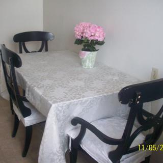 A cozy dining area with a table adorned with a tablecloth and a potted plant centerpiece.