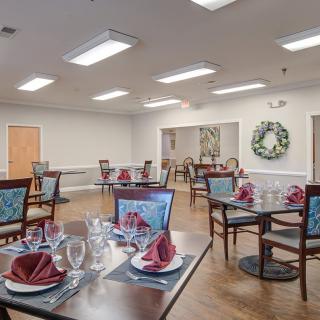 An elegantly set dining room with multiple tables, each adorned with napkins and glassware.