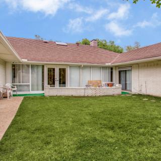 A view of a residential backyard featuring a well-maintained lawn and patio area.