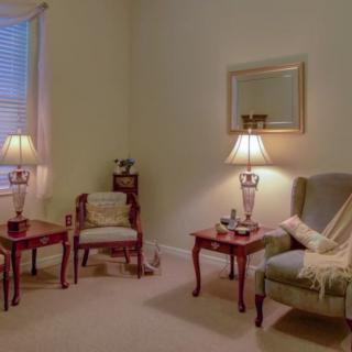 A cozy living room with elegant furniture, including chairs and side tables topped with stylish lamps.