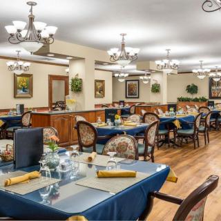 A spacious dining room with elegantly set tables and decorative chandeliers.