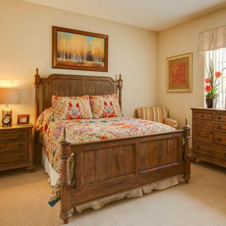 A cozy bedroom featuring a wooden bed frame, nightstands, dresser, and decorative elements.