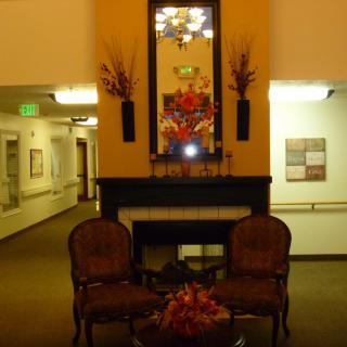 A warmly decorated lobby with a seating area featuring two chairs, a fireplace, and ornate decorations.