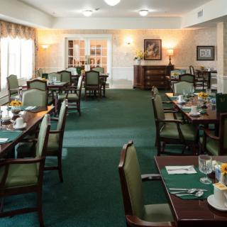 A well-lit dining area with neatly arranged tables and chairs, featuring elegant decor.