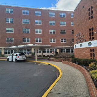 A view of a healthcare facility with a curved driveway and a parked vehicle.