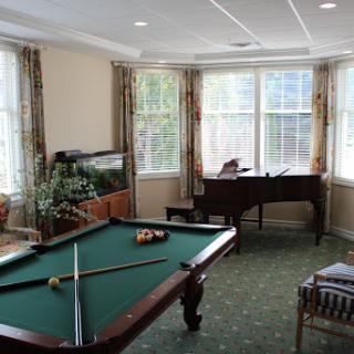 A bright and inviting game room featuring a pool table and piano, perfect for relaxation and entertainment.