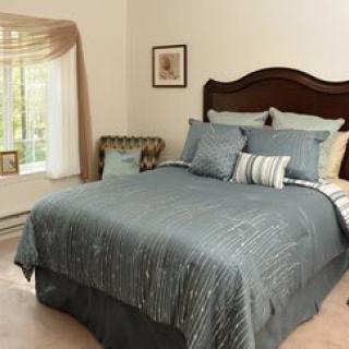 A cozy bedroom with a neatly made bed and a large window with curtains.
